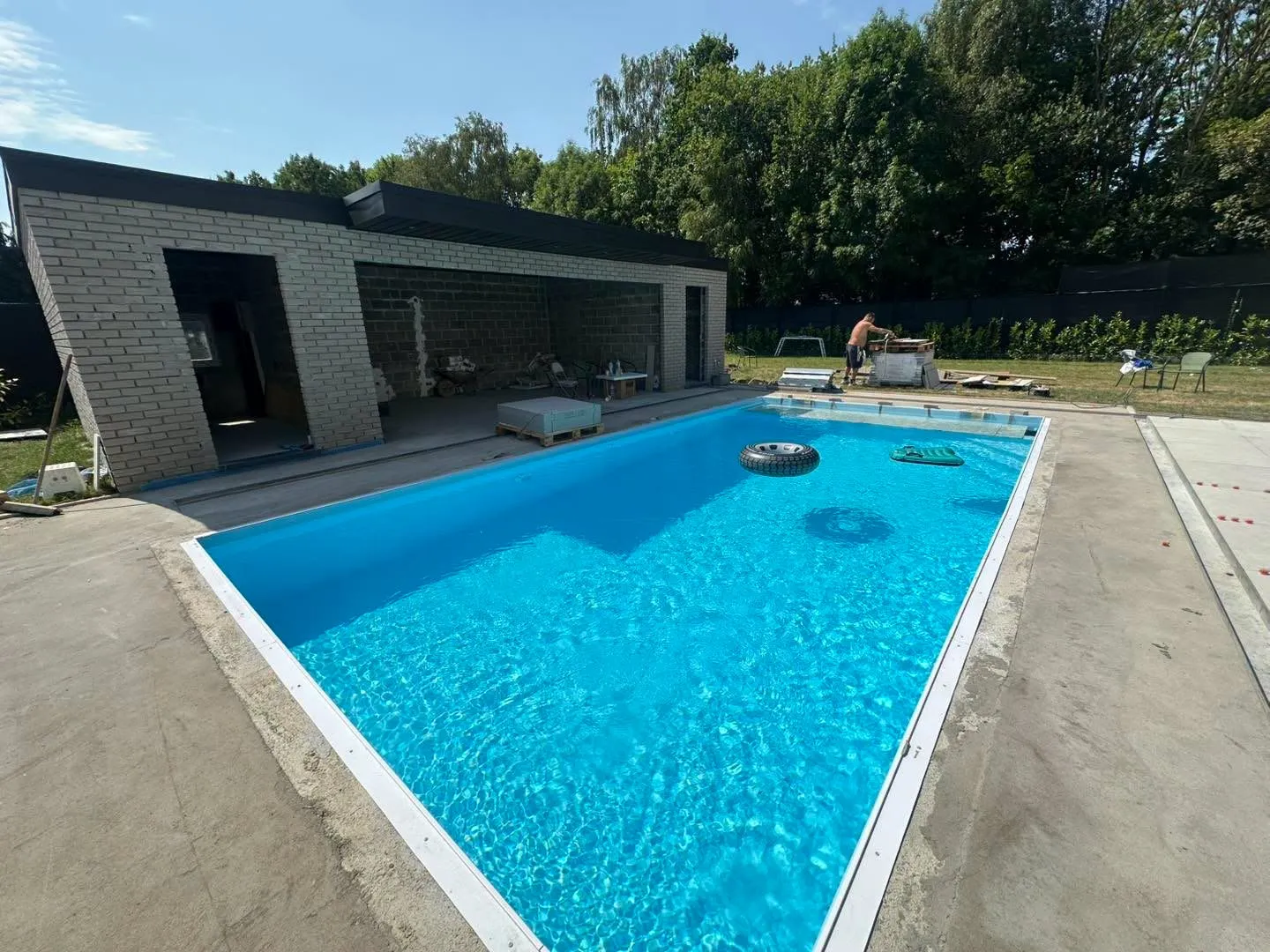 Piscine rectangulaire en cours de finition devant une annexe contemporaine