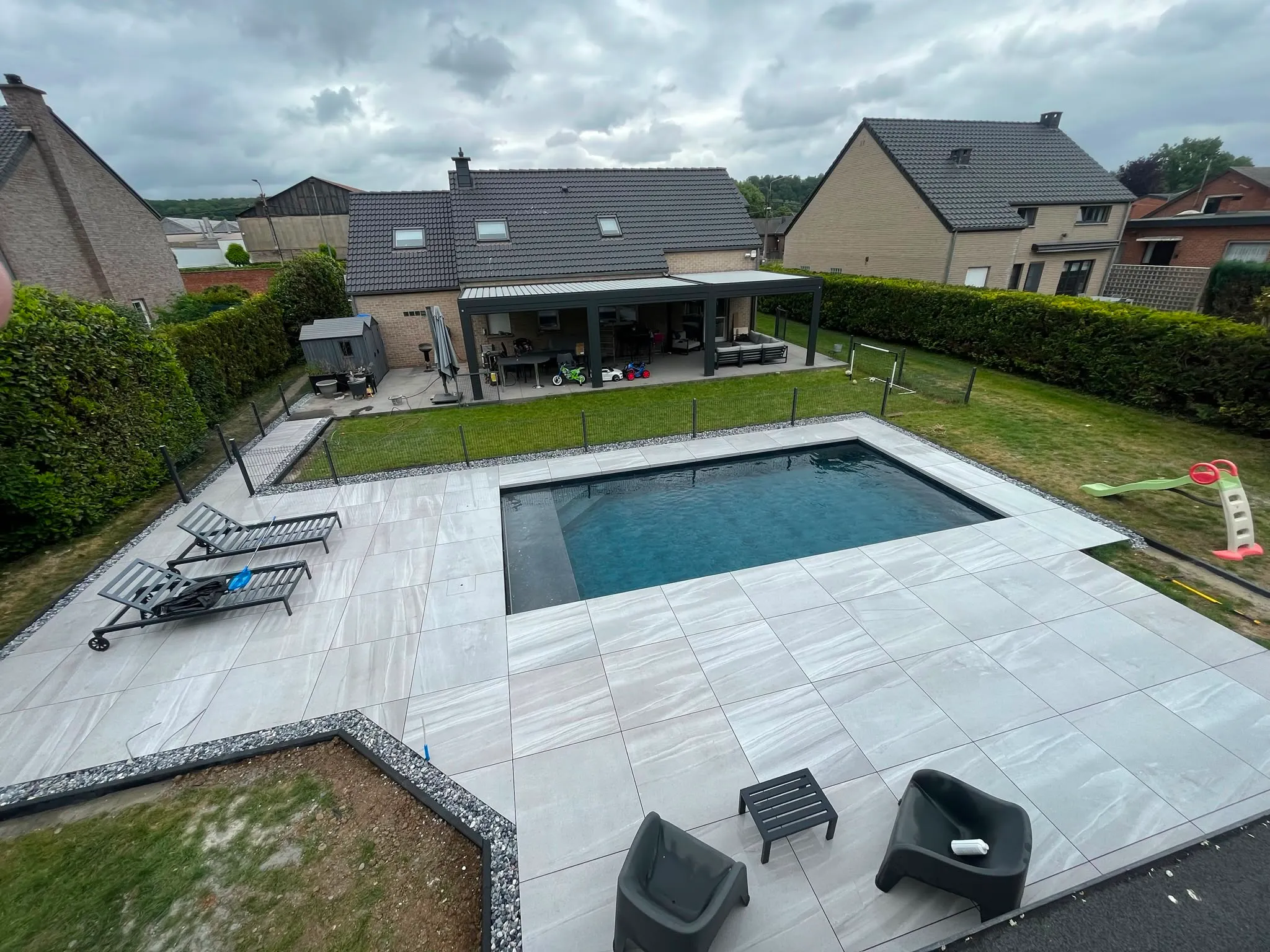 Vue en hauteur d’une piscine entourée d’une vaste terrasse claire