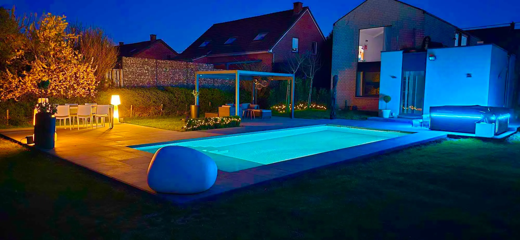 Piscine et jardin éclairés de nuit avec terrasse et pergola