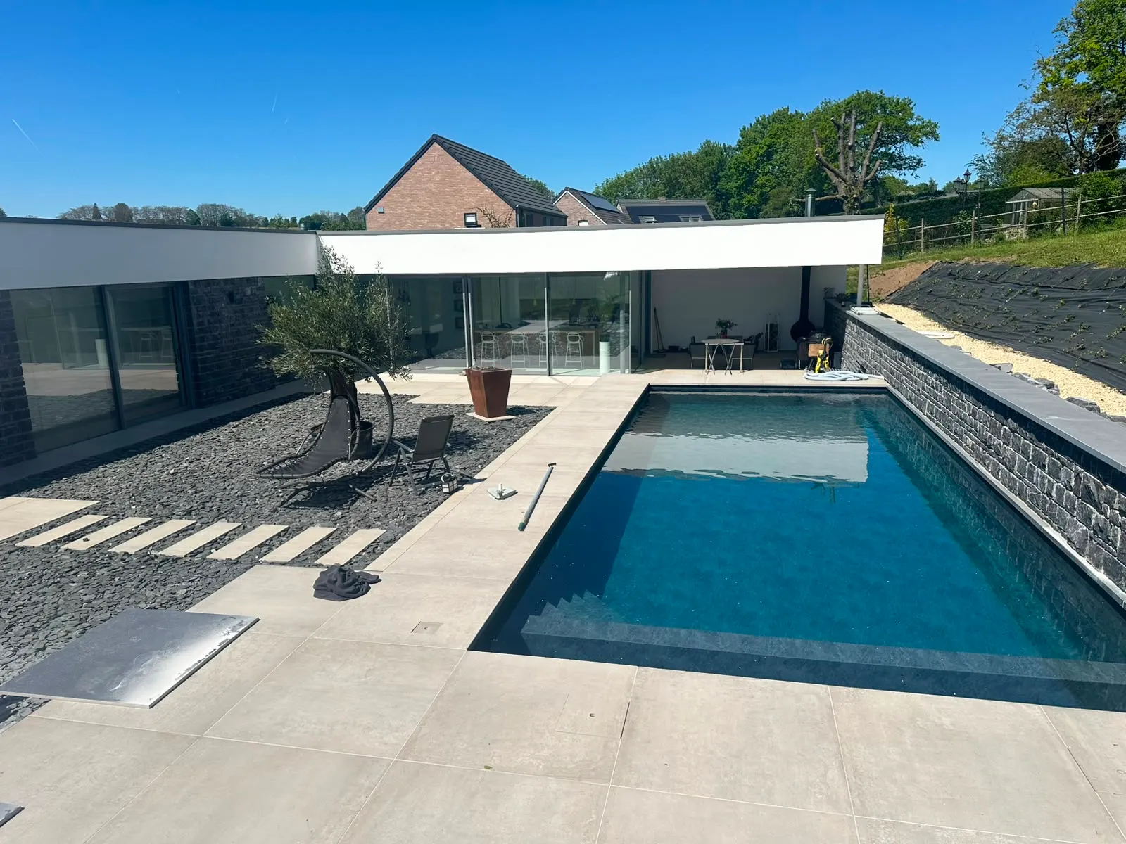 Piscine contemporaine bordée d’un mur en pierre et d’une terrasse claire