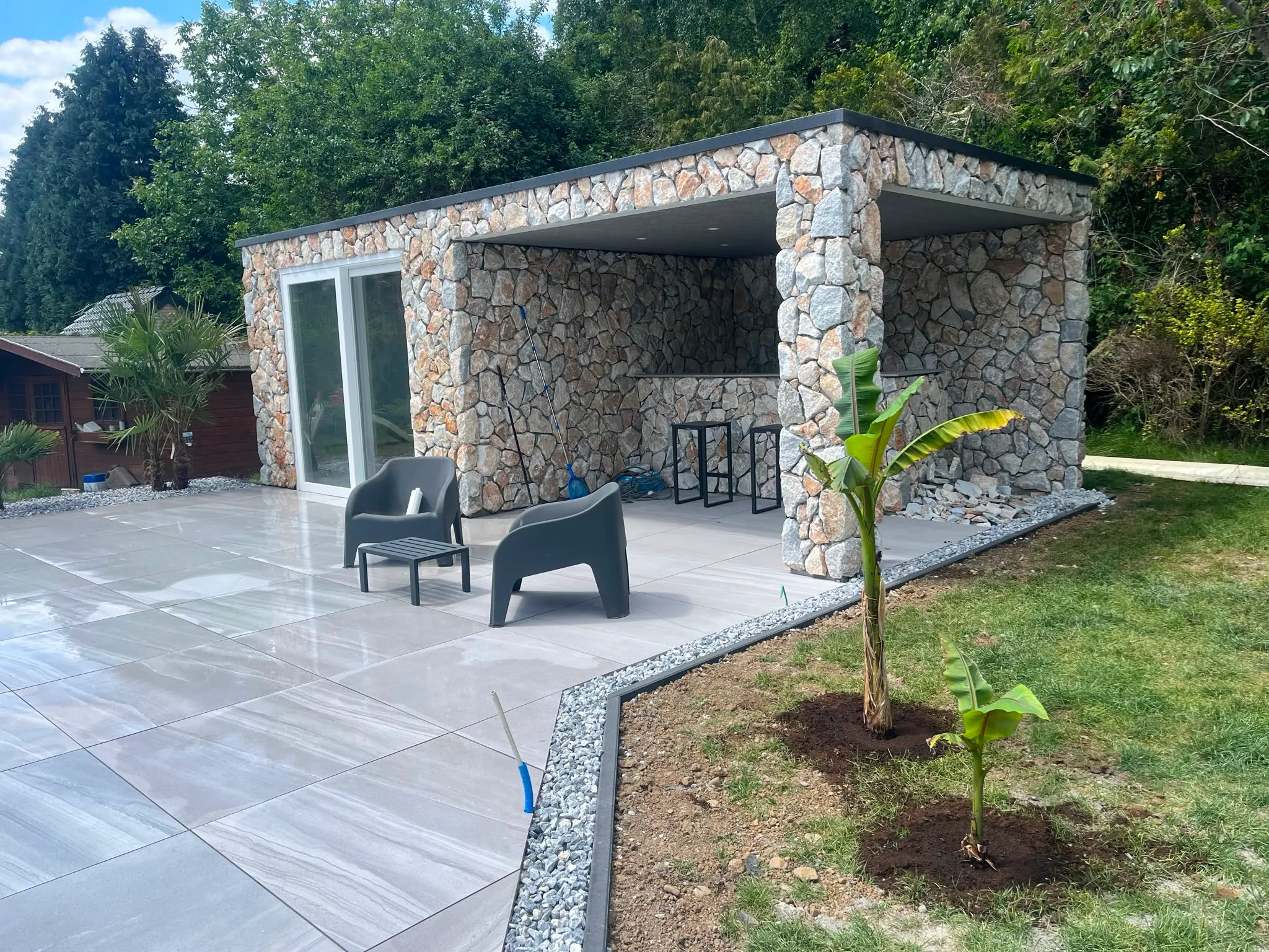 Pool house en pierre et terrasse minérale au bord d’une piscine