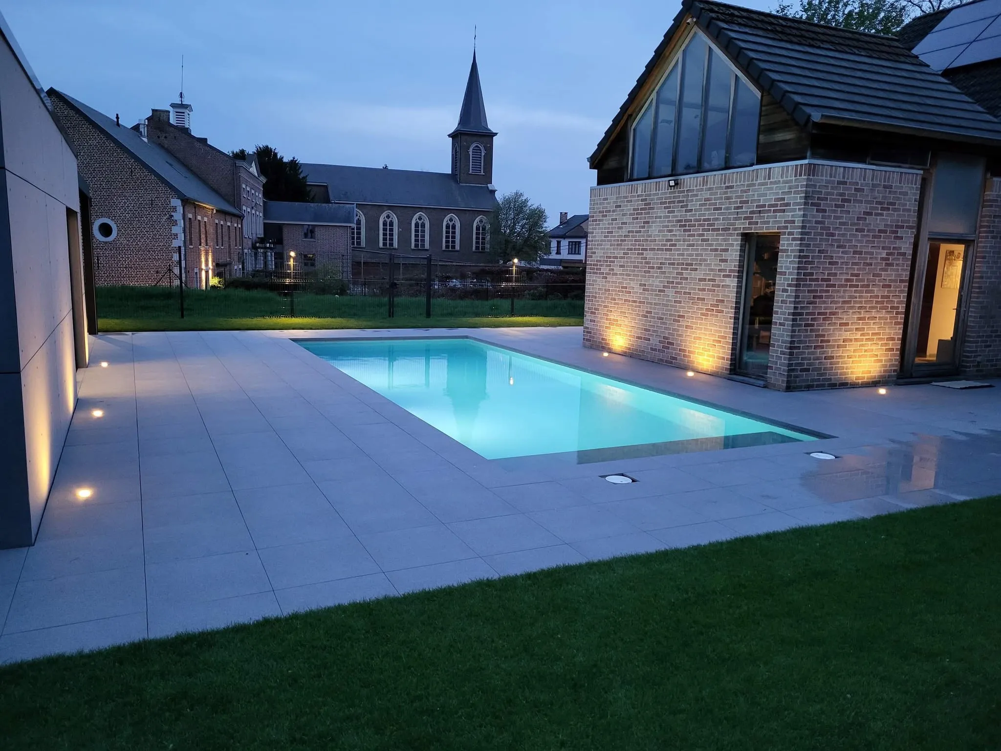 Piscine contemporaine éclairée au crépuscule entre bâtiments modernes