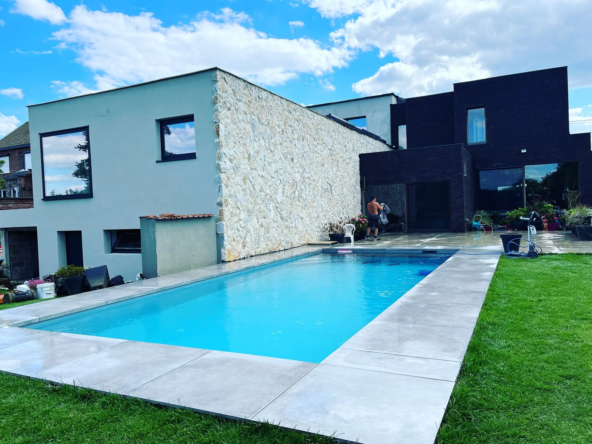 Piscine rectangulaire devant une maison contemporaine mêlant enduit et pierre