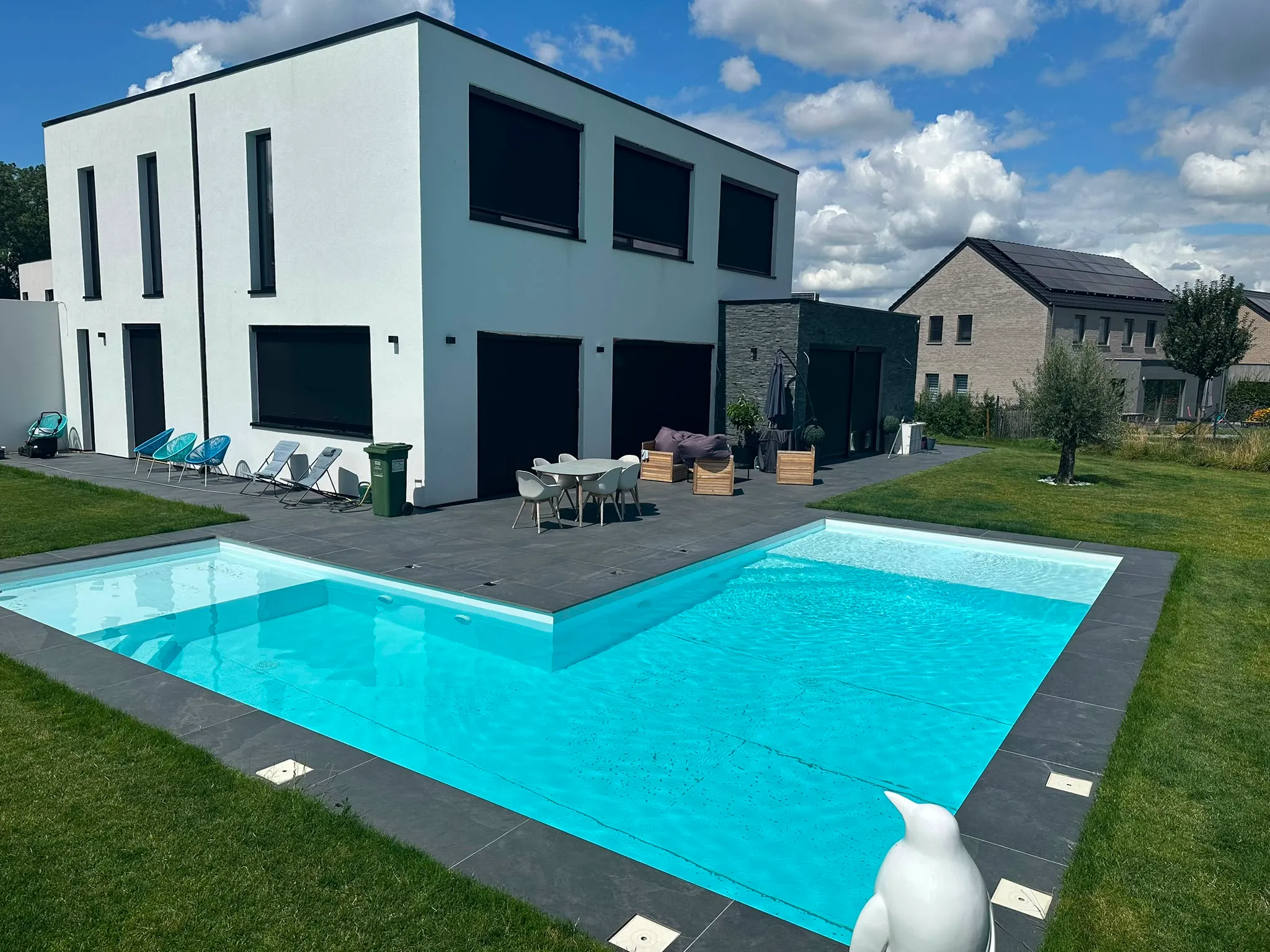 Piscine à géométrie originale devant une maison contemporaine blanche