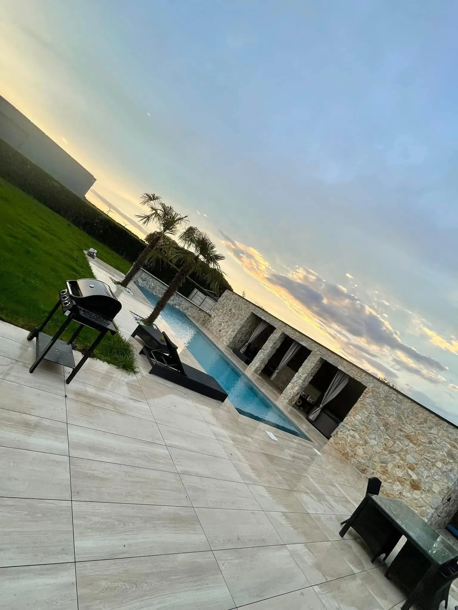 Vue crépusculaire d’une piscine et d’un pool house en pierre