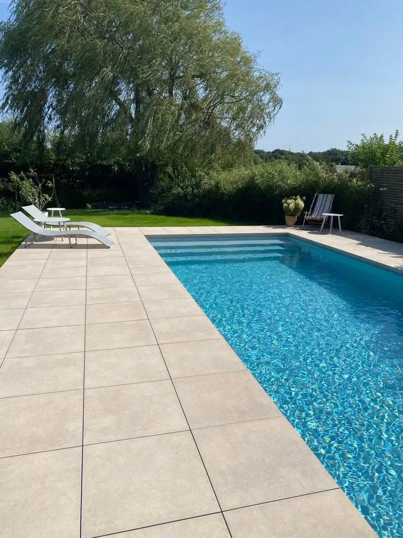 Piscine de jardin avec grand escalier immergé et terrasse beige