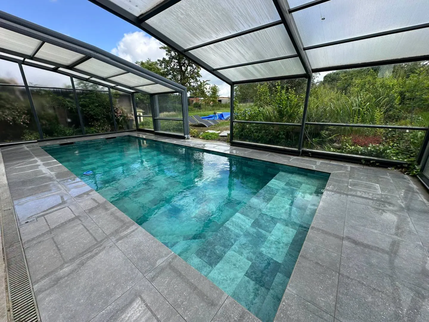 Piscine couverte par un abri vitré avec escalier immergé