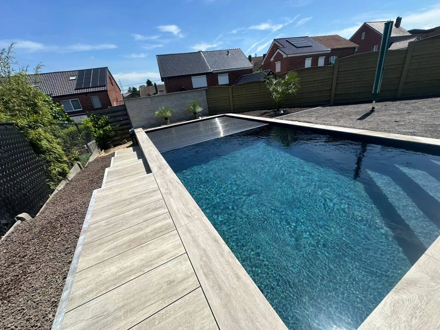 Piscine foncée avec volet automatique dans un jardin paysagé